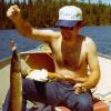 This is a picture of Tom doing what he loved best, next to golf. We were in North Canada at that fly-in lake. 
Here he is on our boat holding
up the Northern Pike that he
caught. They are mean.